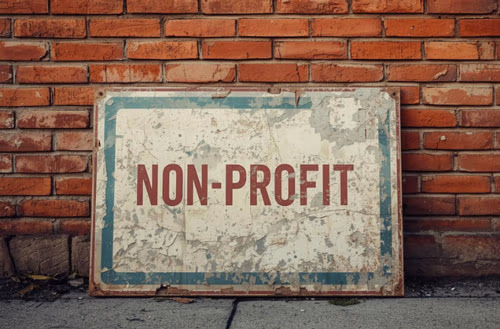 A non-profit sign resting against a brick wall.