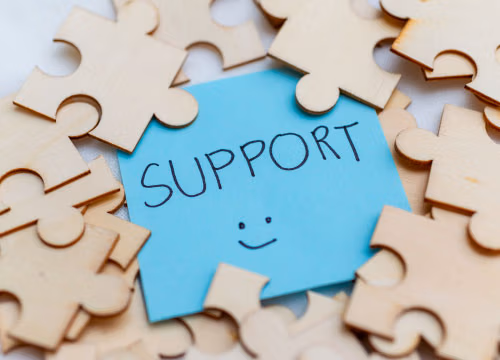Jigsaw puzzle with a support post-it note showing underneath with a happy face.